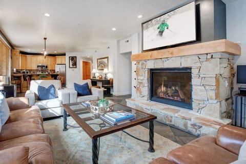 Relax in your spacious living room featuring a stunning stone fireplace, comfortable seating, and entertainment center.