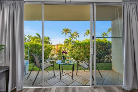The living room opens through wide sliders to a lush garden lanai.