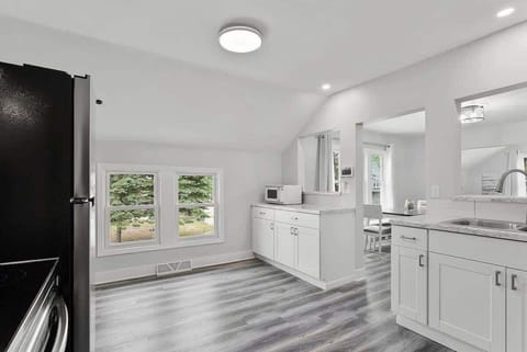 Open kitchen layout with the bathroom and dining room off the kitchen. Kitchen sink overlooks the dining room and living room. Kitchen features granite countertops and a microwave. 