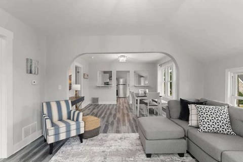 Living room features a couch and chair along with a smart tv. It's open to the dining area that seats 6. 