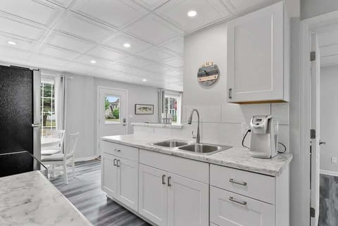 Bright and modern kitchen featuring granite counter tops and coffee pot. It is fully stocked with a full pot and pan set, dish ware, glass wear, silverware, and all the cooking utensils needed to make amazing meals.