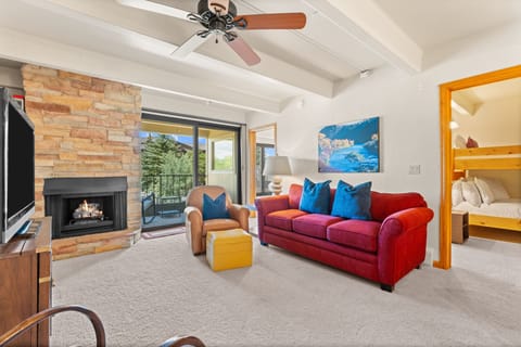 Settle into your cozy living room featuring a stone fireplace and vibrant furnishings—perfect for unwinding after a day of adventure. Step through the glass doors to your private balcony overlooking scenic mountain vistas.