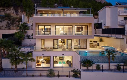The exterior of the Luxurious 5-Bedroom Villa "Million Dreams" is organised over four levels, highlighting the pool and expansive glass doors.