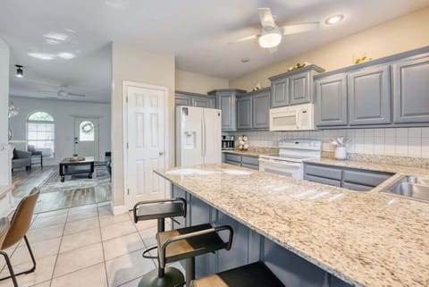 Spacious kitchen with granite countertops, light blue cabinetry, and breakfast‑bar seating—perfect for cooking and casual dining.