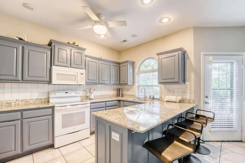 Spacious kitchen with granite countertops, light blue cabinetry, and breakfast‑bar seating—perfect for cooking and casual dining.