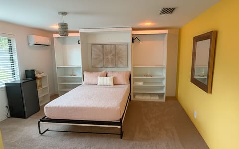 The Gold Room at Garden of Manors, featuring a spacious bed framed by built-in closets, soft lighting, and warm gold accents in Wilton Manors.