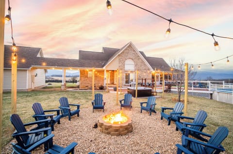 Cozy twilight firepit circle with Adirondack seating, string lights, and hot tub nearby—an inviting outdoor hangout where your group can toast s’mores, swap stories, and soak in the mountain air.