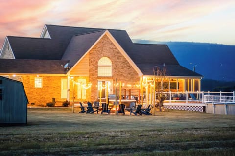 Sunset-view home with glowing string-lit firepit, private pool, hot tub, and wide open mountain panoramas—perfect for unforgettable gatherings under the sky at Luray Vista.