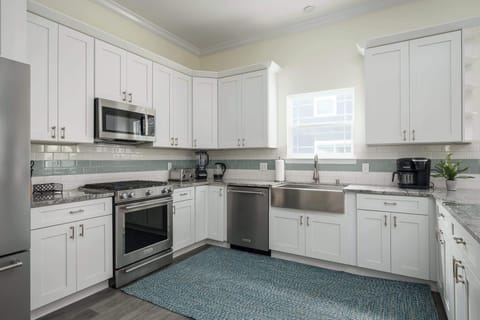 "Prepare feasts in an L‑shaped kitchen with stainless appliances, farmhouse sink and teal rug. It offers plenty of room to create culinary magic. - The Coquina - St. Augustine, FL"