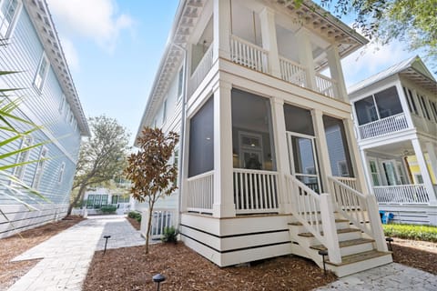 Charming coastal cottage with wraparound porch and white railings in peaceful residential neighborhood.