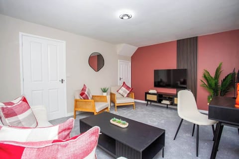 Bright and modern living space with warm coral accents, cozy seating, and a smart TV — the perfect spot to relax after a day of exploring.