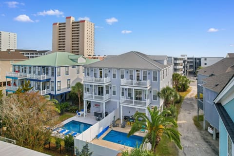 Modern beachside duplex with private pools, tropical landscaping, and balconies in a vibrant coastal neighborhood.
