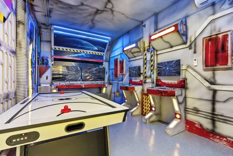 Enter our vibrant game room, where futuristic decor and dynamic lighting ignite excitement. Enjoy friendly competition at the sleek air hockey table, surrounded by colorful accents and imaginative designs for fun-filled evenings.