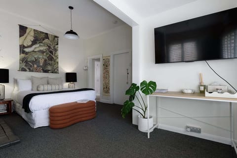 Enjoy movie night from the plush queen bed, complete with an elegant burnt-orange footbench and a large mounted TV.