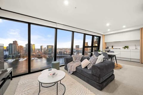 Breathtaking floor-to-ceiling windows wrap around this sophisticated open-plan apartment. Enjoy sweeping river and city views from the plush sofa, seamlessly connecting modern interiors with an iconic urban backdrop.