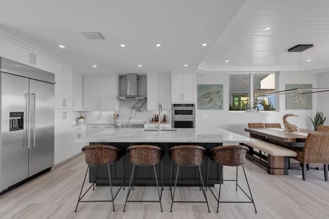The inviting dining area features a stylish table with seating for eight, complemented by an additional four seats at the kitchen island—perfect for family meals and casual gatherings.