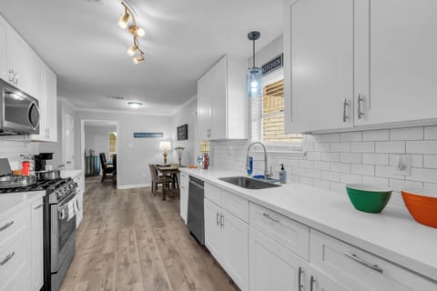 Bright modern kitchen with quartz counters, gas stove, and stainless appliances.