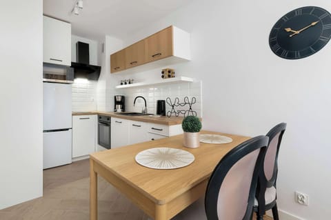 A compact kitchen with white cabinets, wooden countertops, and a small dining table with two chairs.