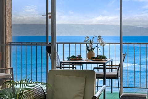 Closer look from indoors highlights the balcony setup, blue skies, and distant landmass across the water.