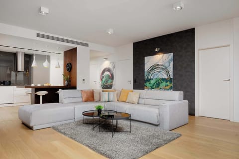 The bright living area with a spacious sofa offers a cosy spot to relax after a day of exploring, enhanced by warm lighting, soft textures and a harmonious mix of modern design elements.