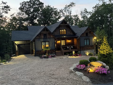 Rustic wooded retreat with warm lighting, porch charm, and private curb appeal
