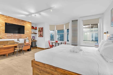 Comfortable king size bed iin an open plan room with workstation area 