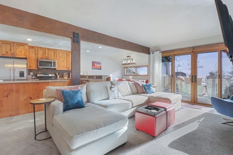 Settle into your spacious mountain retreat where rustic wood beams meet modern comfort. Sink into the plush sectional sofa as natural light floods through floor-to-ceiling windows, revealing stunning views of the surrounding peaks and valley below.