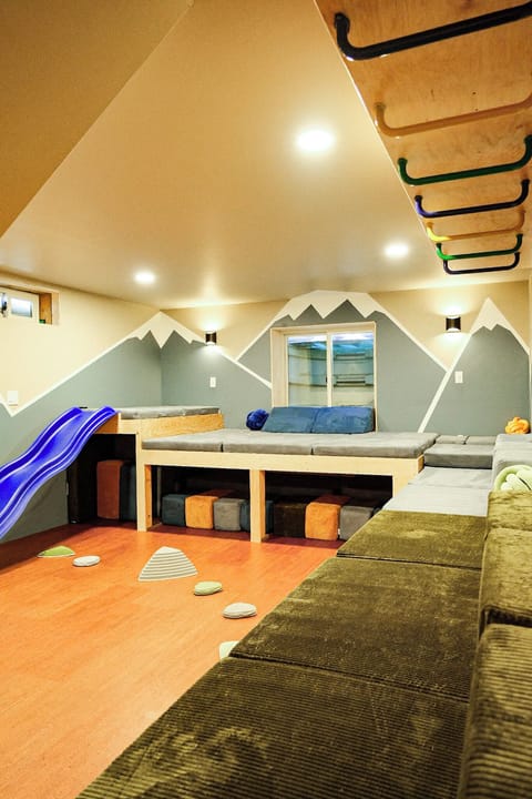 Adventure-themed ultra fort building room with rock climbing wall, slide, and monkey bars.