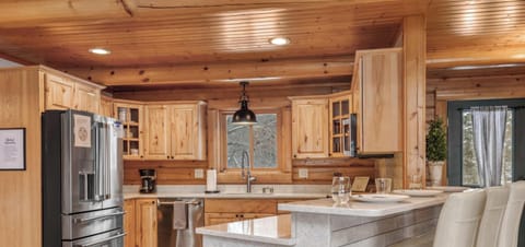 Fully stocked kitchen with 3 barstools at the breakfast bar, complimentary coffee, tea, and sugar station, and an open concept into the living room and dining room.