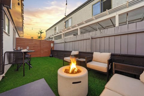 Chic outdoor firepit lounge with turf and comfy seating.