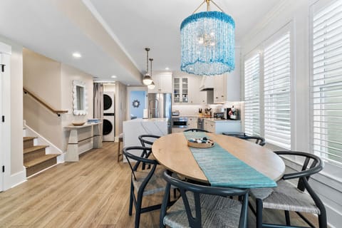A light-filled space featuring a statement blue chandelier, natural wood tones, and relaxed seating—perfect for seaside-inspired gatherings.