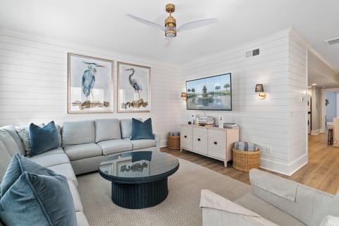 A bright, beach-inspired living space featuring soft neutrals, ocean-toned accents, and stylish artwork for a relaxed yet refined retreat.