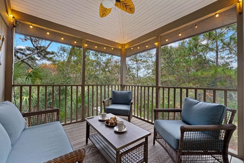 This screened-in porch offers a peaceful outdoor retreat surrounded by lush, wooded views.