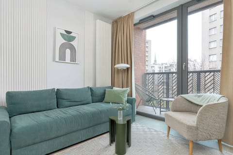 Bright living room with a fold-out corner sofa, balcony doors, and modern decor.