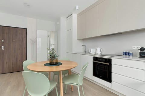 Minimalist kitchenette with oven, cabinets, and small dining table.