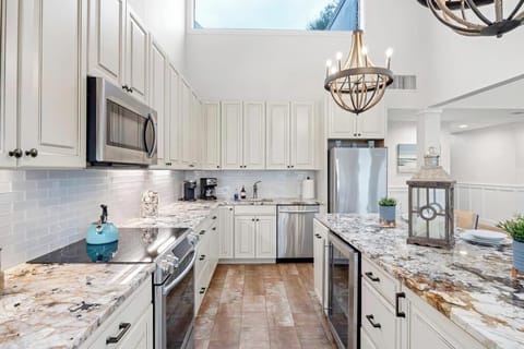 Open kitchen w/ generous counters and seating, designed for cooking and connection.