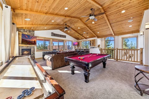 Spacious game room and bar with pool table, shuffleboard, foos ball, bar, TV, fireplace and more
