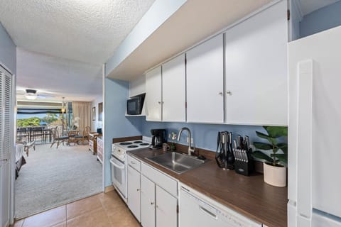 Cook with ease in the bright kitchen featuring white cabinets, full appliances, and tropical charm