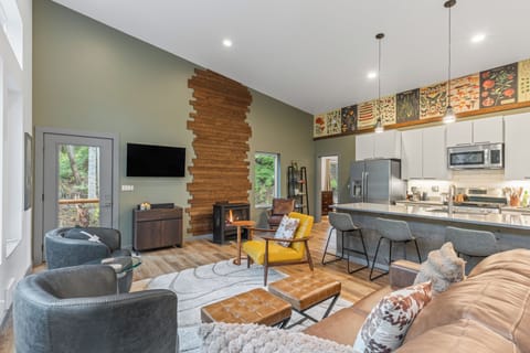 Living room and kitchen showcasing a wood-slat accent wall and a large TV.
