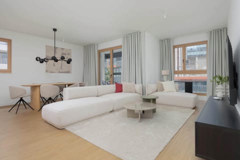 A bright living room with a comfortable sofa, armchairs, and large windows letting in plenty of natural light. The space is designed for relaxation and everyday comfort.