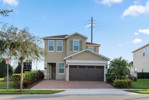 This charming home features a light exterior with warm beige tones, complemented by lush landscaping and a spacious brick driveway. Large windows invite natural light, creating a welcoming atmosphere that enhances your stay.
