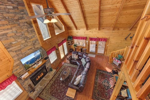 Cozy up in your mountain retreat's living room with soaring timber ceilings, crackling stone fireplace, and leather seating perfect for relaxing evenings.