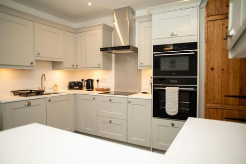 Kitchen with fitted cupboards, oven and microwave, sink, hob, extractor hood, toaster
