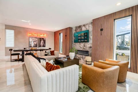 Living space built for groups with a wraparound sectional, paired armchairs, and a fireplace that anchors the room, all open to the kitchen and dining area