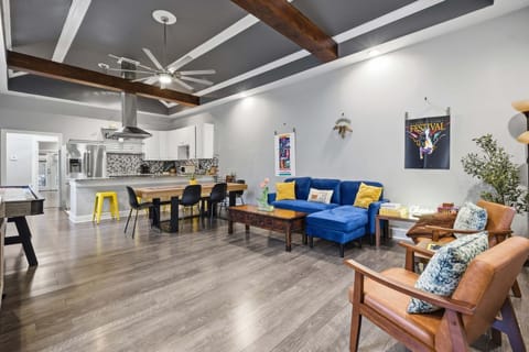 Spacious open-plan room combining living-room seating, a dining table, breakfast bar, and full kitchen.