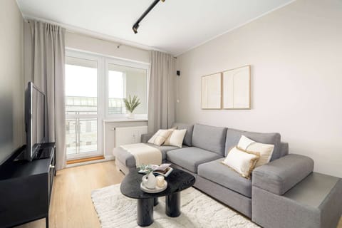 Inviting living room with refined grey seating, soft drapery, and a warm wooden floor.
