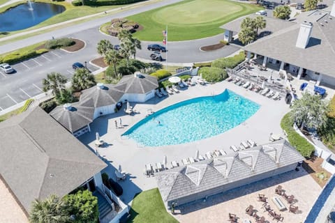 Aerial view of pool with lounge chairs beside golf course greens