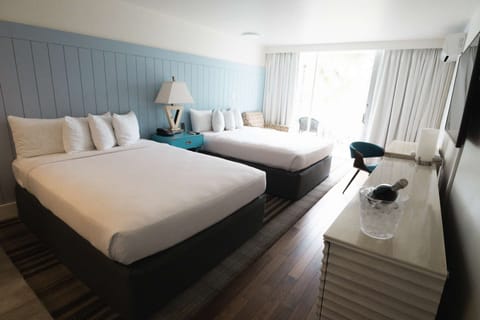 Spacious room with two queen beds and a balcony view of palm trees