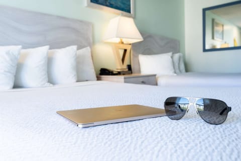 Laptop and sunglasses resting on neatly made bed