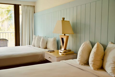 Twin beds beside light blue wall and balcony area